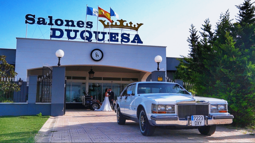 Entrada de Salones Duquesa con coche clásico blanco y pareja de novios en el acceso.