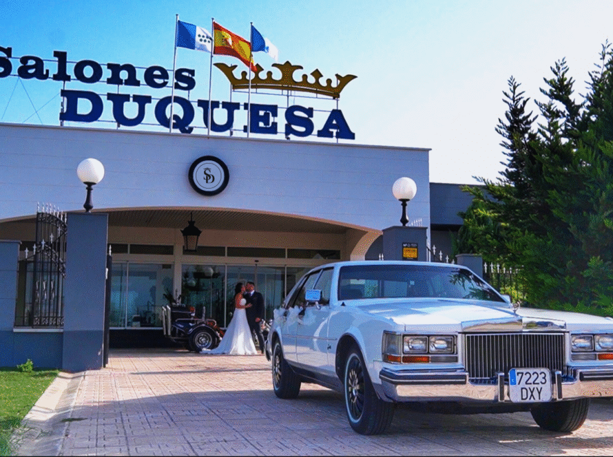 Entrada de Salones Duquesa con coche clásico blanco y pareja de novios en el acceso.