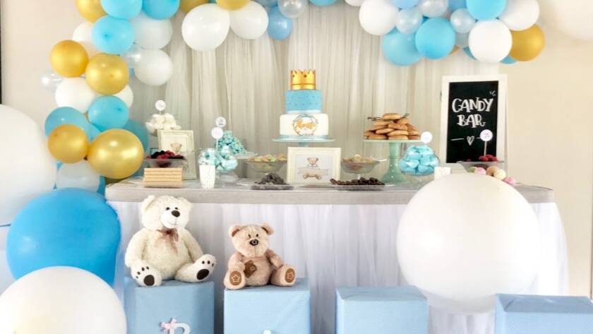 Candy bar de baby shower con arco de globos azules y dorados y bloques BABY.