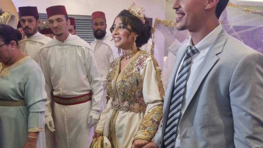 Novios con traje tradicional marroquí caminando entre invitados.